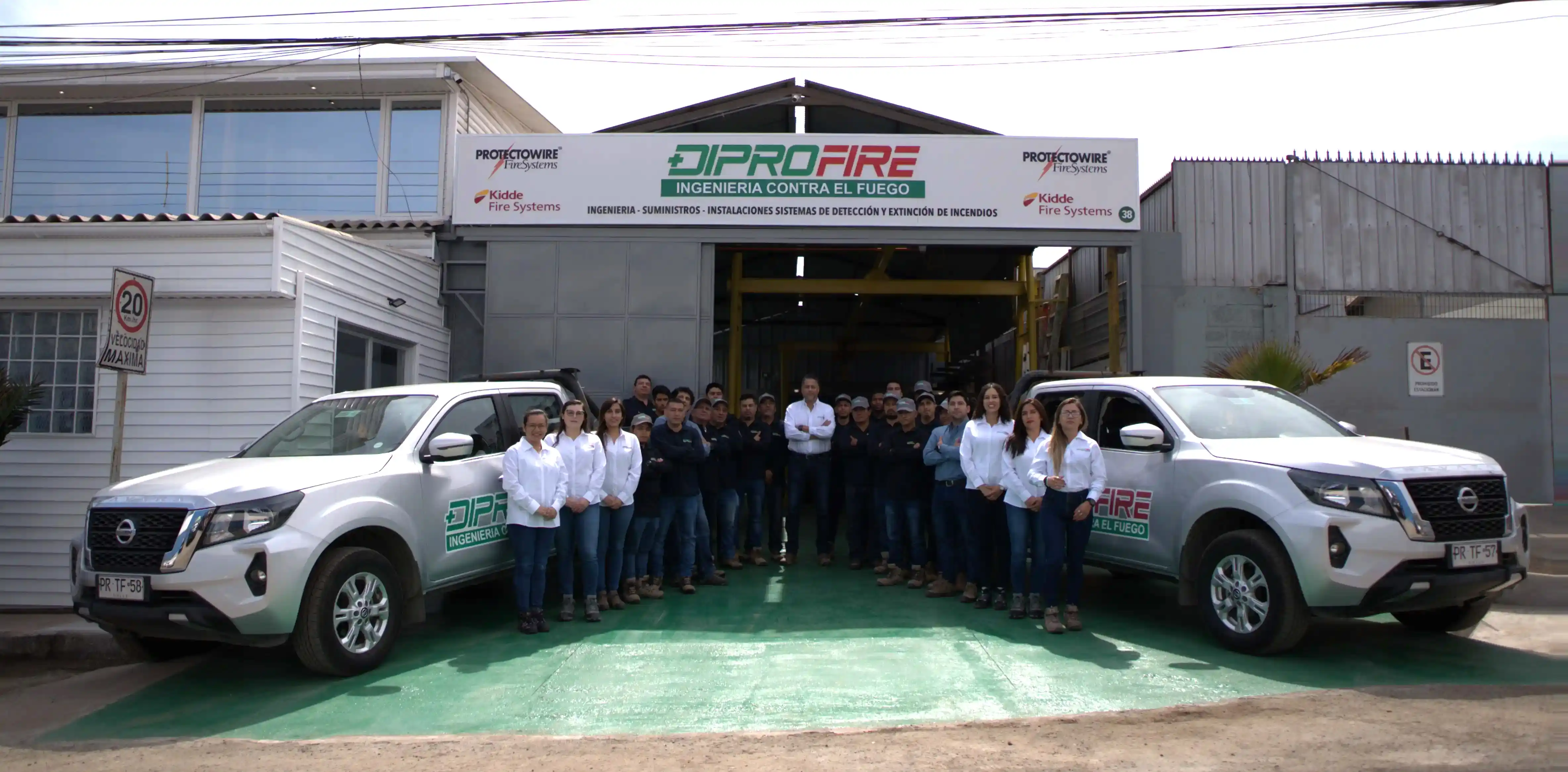 Equipo Diprofire posando frente a las oficinas, con dos camionetas de la empresa estacionadas a ambos lados.